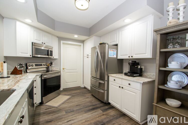 A kitchen with white cabinets and a refrigerator.