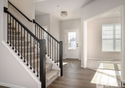 A staircase with a black railing leads to a white door.