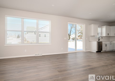 A spacious, empty room with wooden floors and large windows.