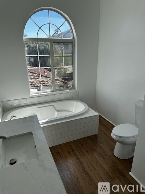 A bathroom with a large window and a white bathtub.