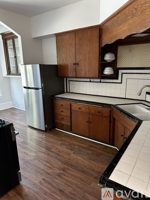 A kitchen with wooden cabinets and a black fridge.