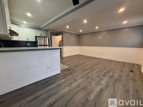 A spacious kitchen with white cabinets and a wooden floor.