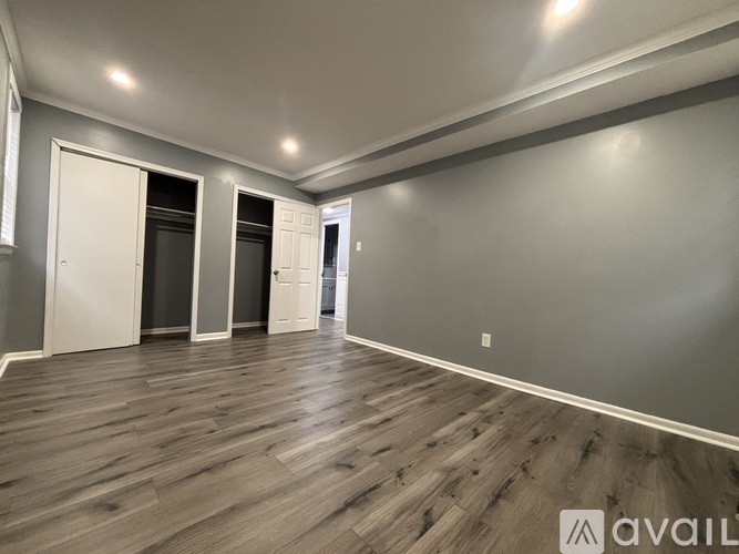 A spacious room with wooden flooring and white walls.