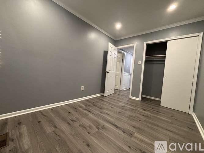A room with wooden flooring and two doors, one of which is open.