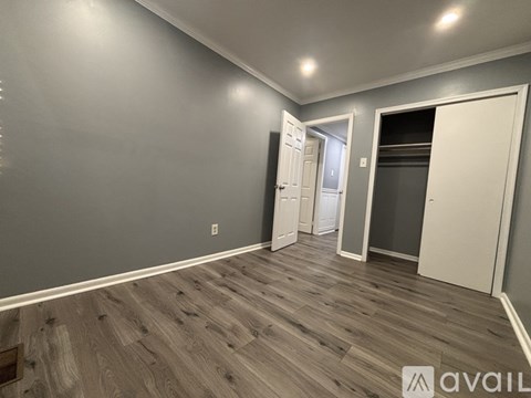 A room with wooden flooring and two doors, one of which is open.