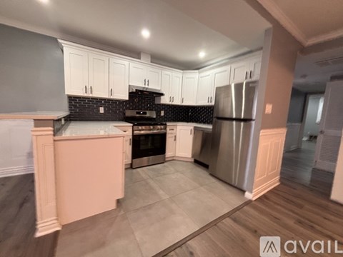 A kitchen with white cabinets and a black backsplash.