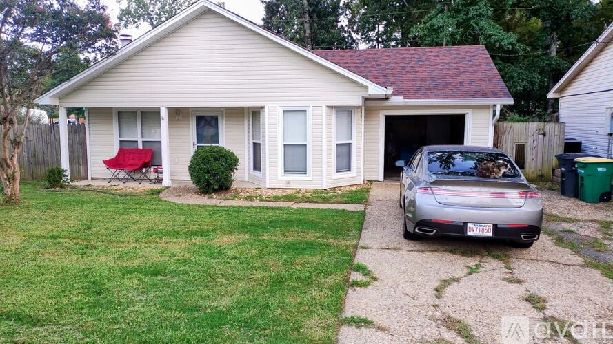 A silver car is parked in front of a house.