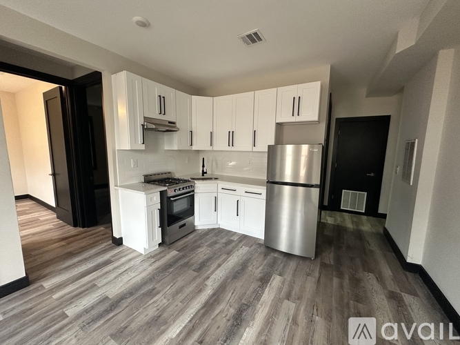 A kitchen with white cabinets and a wooden floor.