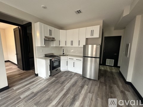 A kitchen with white cabinets and a wooden floor.