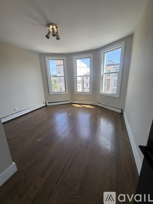 A room with wooden floors and three windows.