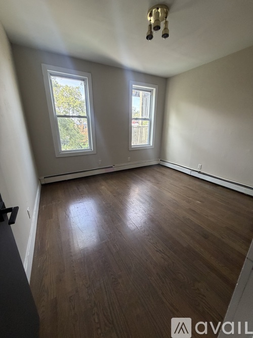 A room with wooden floors and two windows.