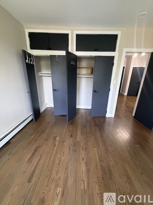 A room with wooden flooring and a wall with a row of cupboards.