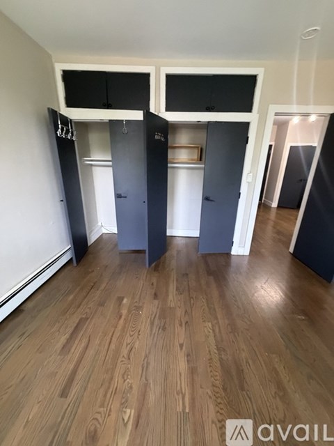 A room with wooden flooring and a wall with a row of cupboards.