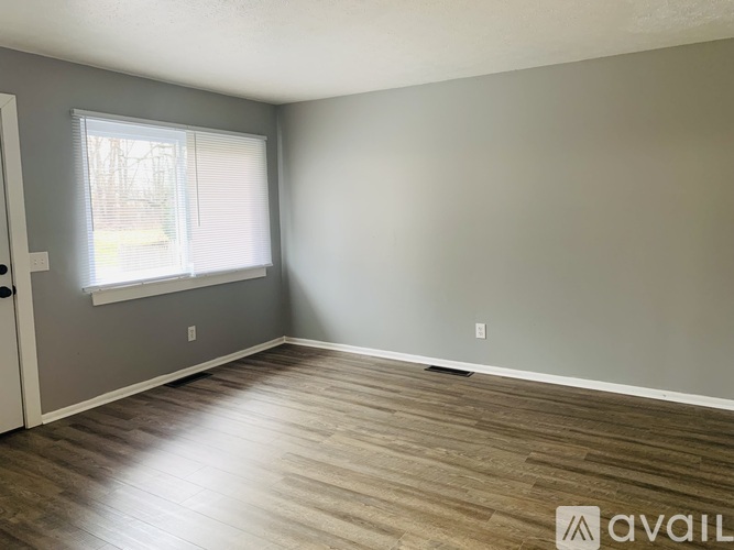 A room with wooden flooring and a window with blinds.
