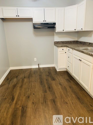 A kitchen with white cabinets and a wooden floor.