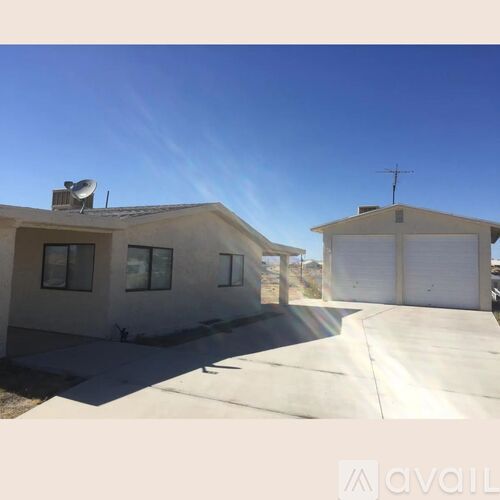 A house with a satellite dish on the roof and a driveway leading to a garage.