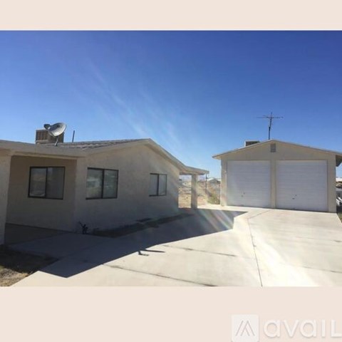 A house with a satellite dish on the roof and a driveway leading to a garage.