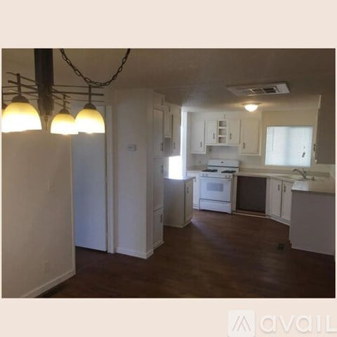 A kitchen with white cabinets and a wooden floor.