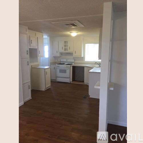 A kitchen with white appliances and wooden floors.