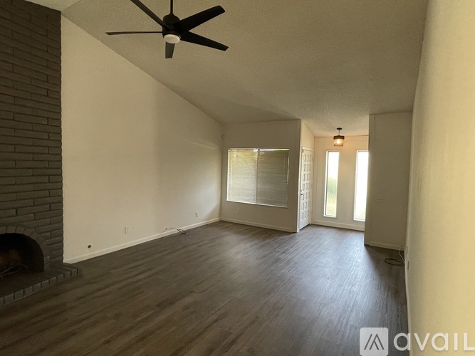 A room with a ceiling fan and a brick fireplace.