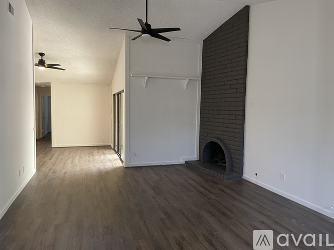A room with a ceiling fan and a fireplace.