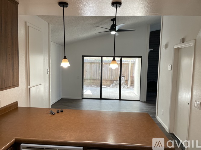 A living room with a ceiling fan and sliding glass doors.