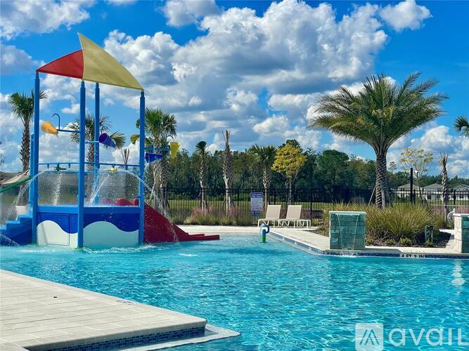 A pool with a water slide and a wooden deck.