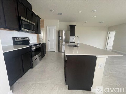 A kitchen with black cabinets and a white countertop is available.