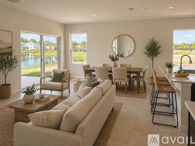 A living room with a large couch, a coffee table, and a view of a lake through the windows.