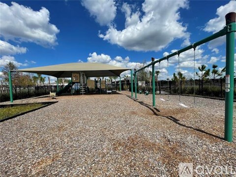 A playground with a swing set and a green fence.