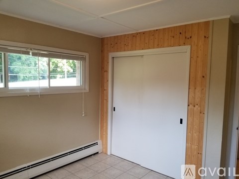 A room with a white door and a window with blinds.