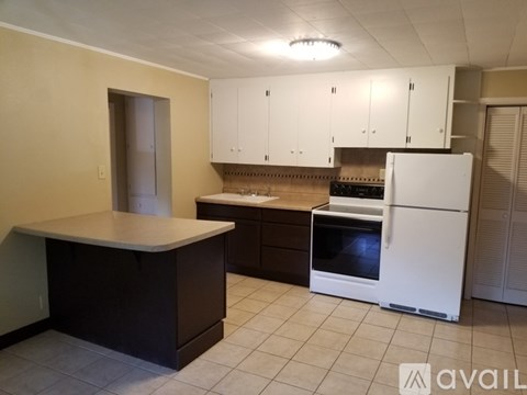 A kitchen with white appliances and black countertops.