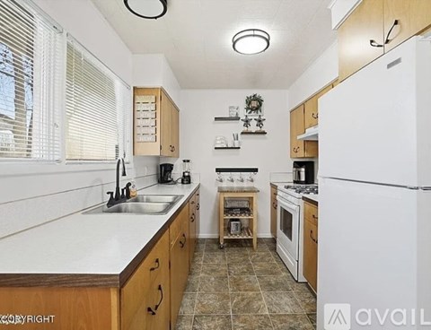 A kitchen with a white refrigerator, wooden cabinets, and a tiled floor.