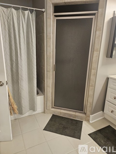 A bathroom with a glass door shower enclosure and a white door.