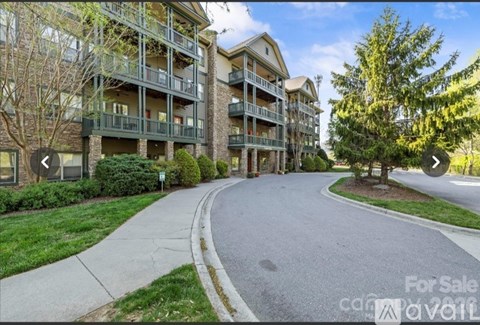 A multi-story apartment building with a for sale sign in front.