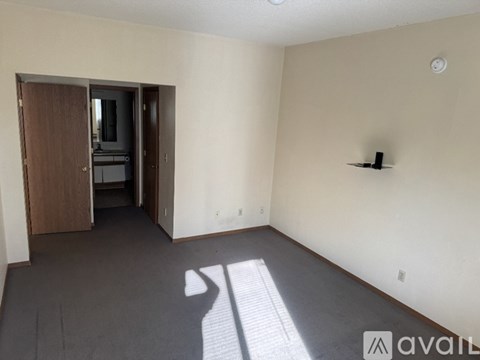A room with a carpeted floor and a wooden door leading to another room.