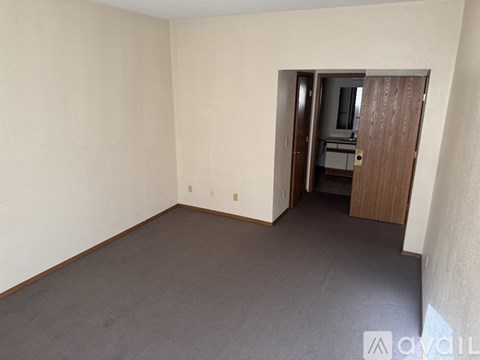 A room with a carpeted floor and a doorway leading to another room.