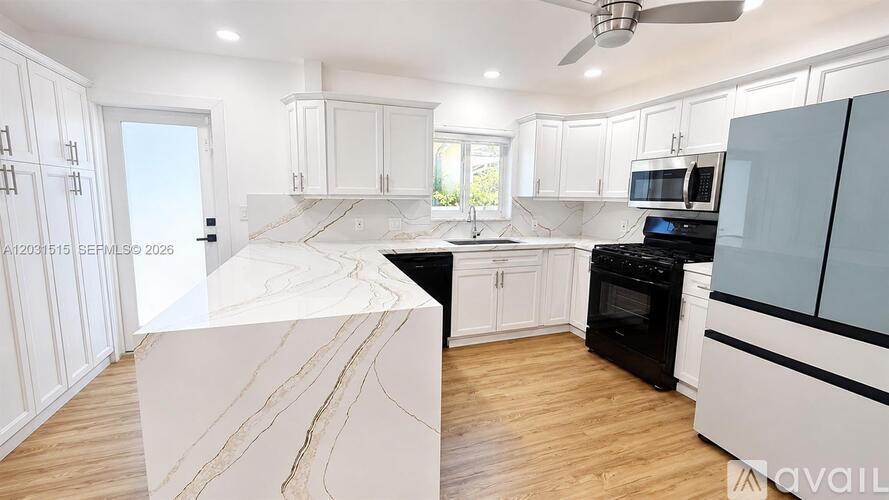 A modern kitchen with a marble island and black appliances.