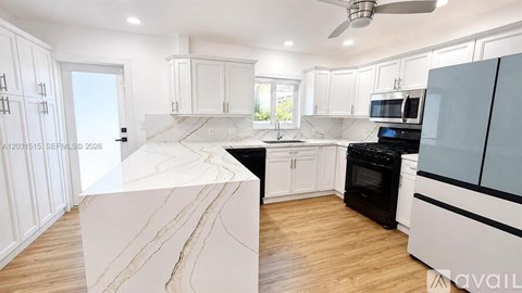 A modern kitchen with a marble island and black appliances.