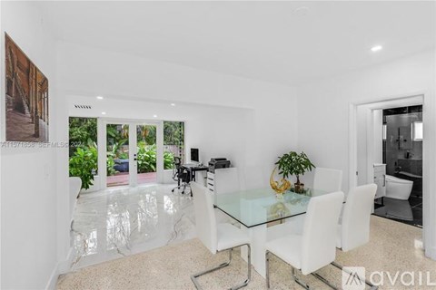 A modern dining room with a glass table and white chairs.