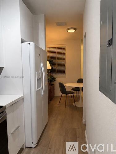 A kitchen with a white refrigerator and a dining table with chairs.
