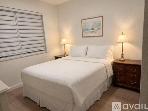A bedroom with a white bed and two lamps on either side of the bed.