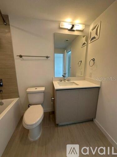 A bathroom with a toilet, sink, and mirror.