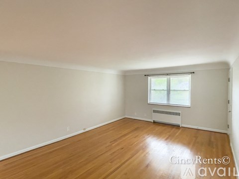 A room with wooden floors and a window with blinds.