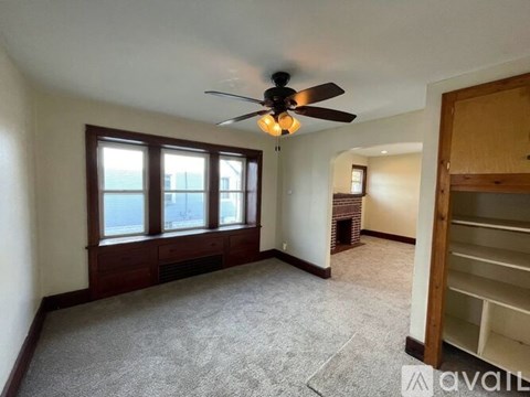 A room with a ceiling fan and a window overlooking a building.
