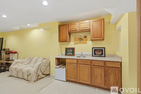 A kitchen with yellow walls and wooden cabinets is available for rent.