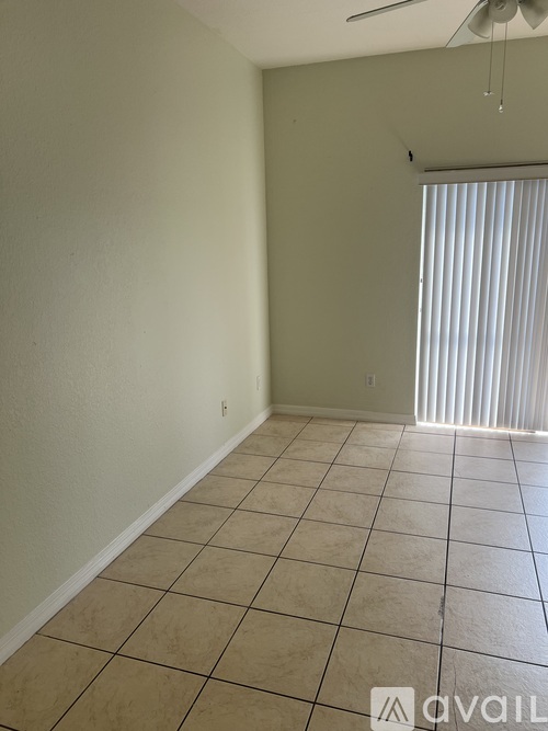 A room with beige tiled flooring and a window with blinds.
