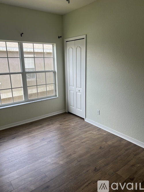 A room with a white door and a window with a view of a building outside.