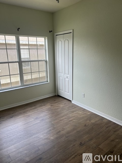 A room with a white door and a window with a view of a building outside.