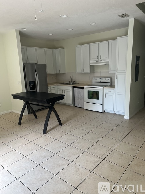 A kitchen with white cabinets and a black island.